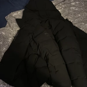 Svart dunjacka från Peak Performance - Säljer en svart dunjacka från sail racingJackan har en stilren design med lång ärm och dragkedja. Perfekt för kalla dagar med sin varma och skyddande stil. Äkta jacka 