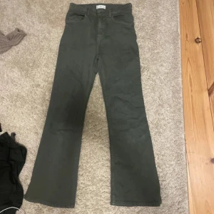 Gröna byxor från MNG - Snygga gröna byxor från MNG med hög midja och bootcut-stil. Perfekta för en trendig look. Byxorna har en klassisk design med knappar och dragkedja framtill.