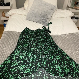 Svart och grön klänning med knytband - Snygg svart klänning med grönt blommönster och knytband i midjan. Perfekt för en somrig look. Klänningen har en omlott-design som ger en fin passform.