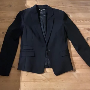 Svart kavaj från stockh LM  - Elegant svart kavaj från stockh LM med klassisk design. Kavajen har en enkelknäppning och två fickor framtill. Perfekt för en stilren look.