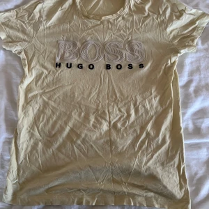 Gul t-shirt från Hugo Boss - Säljer en gul t-shirt från Hugo Boss med stor BOSS-logga på bröstet. T-shirten är kortärmad och har en rund halsringning. Perfekt för en avslappnad stil.