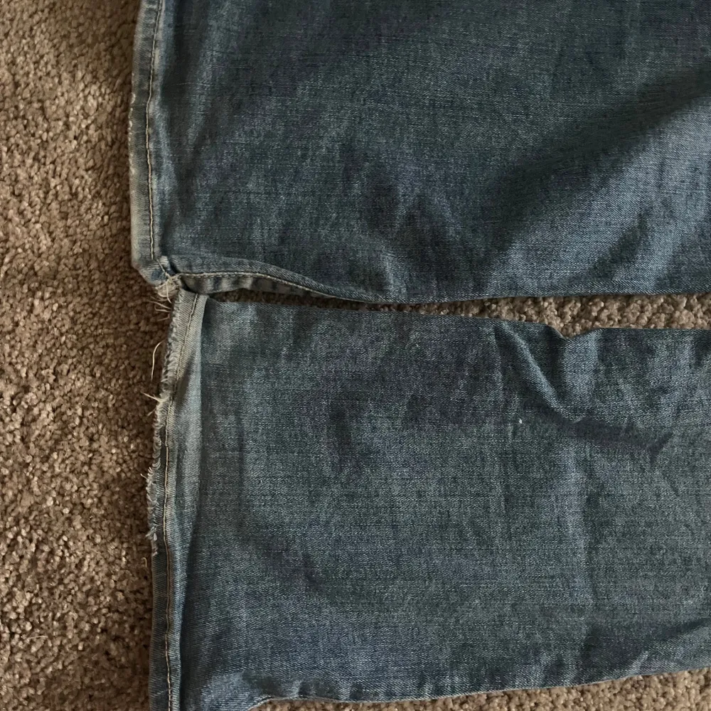 Säljer ett par klassiska blå bootcut jeans med låg midja. De har en snygg tvätt och är perfekta för en avslappnad stil. Jeansen har knappar och dragkedja framtill. De är sydda på båda insida lår pågrund av att de va hål. De har bara sytts en gång och jag har aldrig märkt av att sömmarna går upp. Storlek W 26 L 30. . Farkut & Housut.