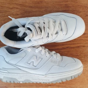 Vita sneakers från New Balance - Säljer ett par vita New Balance 550 sneakers. De har en klassisk design med snörning och en bekväm sula. Perfekta för en stilren look.