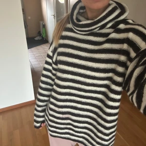 Randig stickad tröja från NA-KD - Säljer en mysig randig stickad tröja från NA-KD i svart och vitt. Tröjan har en hög krage och långa ärmar, perfekt för kyliga dagar. Den är i storlek S och passar bra för en avslappnad stil. Perfekt för höst och vinter!