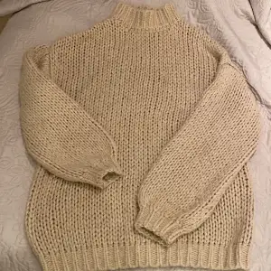 Mysig beige stickad tröja från NA-KD i storlek S/M. Perfekt för kyliga dagar med sin tjocka och varma design. Tröjan har en hög krage och långa ärmar med ribbade muddar. Passar perfekt till både vardag och mysiga hemmakvällar. 🧶✨