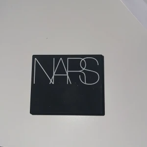 NARS Rouge Orgasm - Säljer en superfin rouge från NARS i nyansen Orgasm. Den har en härlig persikorosa färg med ett subtilt skimmer som ger en fräsch och strålande look. Perfekt för att ge kinderna lite extra glöd! Kompakt och lätt att ta med sig i väskan. Den är inte alls använd och jag säljer den eftersom att jag redan har en annan.