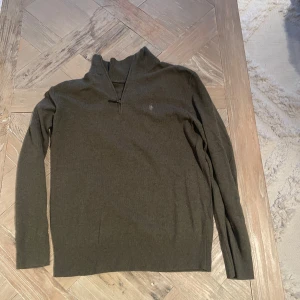 Olivgrön tröja från Polo Ralph Lauren - Säljer en stilren olivgrön tröja från Polo Ralph Lauren i mycket bra skick. Tröjan har en halv dragkedja och är långärmad, perfekt för höst och vinter. Den är tillverkad i ett mjukt material som känns skönt mot huden. Passar både till vardags och lite finare tillfällen.
