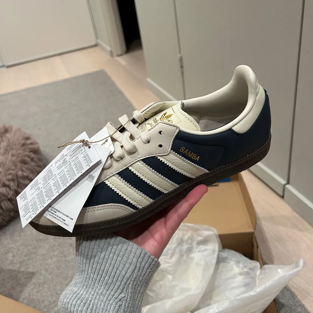 Säljer ett par sprillans nya Adidas Samba sneakers i beige och blå. De har snygg snörning och den klassiska tre-randiga designen. Perfekta för både vardag och fest! Skorna kommer i originalkartong med extra skosnören. Säljer på grund av att dem inte passade mig! . Skor.