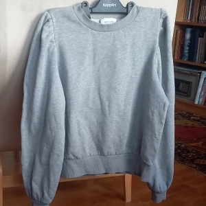 Grå sweatshirt från Second Female - Säljer en stilren grå sweatshirt från Second Female. Den har en klassisk rund hals och långa ärmar med ribbade muddar. Perfekt för en avslappnad look eller som lager under jackan. Supermjuk och bekväm!