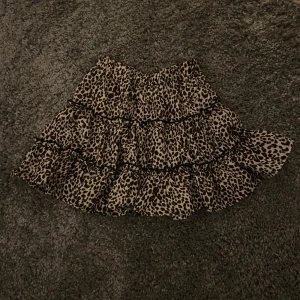 Leopardmönstrad volangkjol - Säljer en superfin leopardmönstrad kortkjol med volanger. Perfekt för en utekväll eller fest! Kjolen har en elastisk midja för en bekväm passform. Den är i mycket bra skick och redo för nya äventyr. 🐆✨