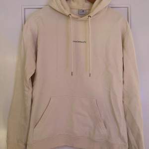 Säljer en stilren beige hoodie från NN07 i mycket bra skick. Den har en klassisk design med känguruficka och justerbar huva med dragsko. Perfekt för både vardag och mysiga stunder. Texten 'No Nationality' pryder bröstet för en minimalistisk look.