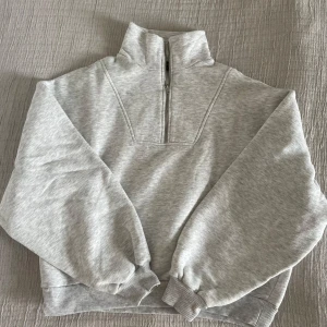 Grå half-zip tröja Ginatricot  - Säljer en supermysig grå halvzip tröja i mycket bra skick. Perfekt för kyliga dagar med sin höga krage och långa ärmar. Den är gjord i mjukt material och har ribbade muddar vid ärmslut och nederkant. Passar perfekt till både vardag och mysiga hemmakvällar! Storlek M men passar S beroende på hur mycket oversize man vill ha den 💕