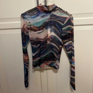 Mönstrad mesh-topp från Bik Bok - Säljer en supercool mönstrad mesh-topp från Bik Bok i storlek XS. Toppen har långa ärmar och ett abstrakt mönster i olika färger som blå, grön och brun. Perfekt för en utekväll eller som ett statement-plagg i garderoben. Toppen är oanvänd med lappen kvar. 