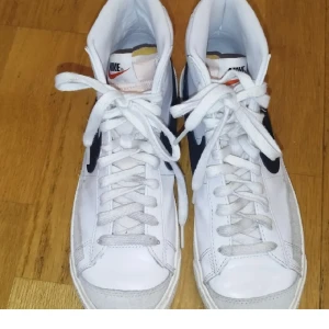 Nike blazers - Ett par vita Nike blazers med svart nike märke. Den är sparsam använd med väldigt få användningar. 