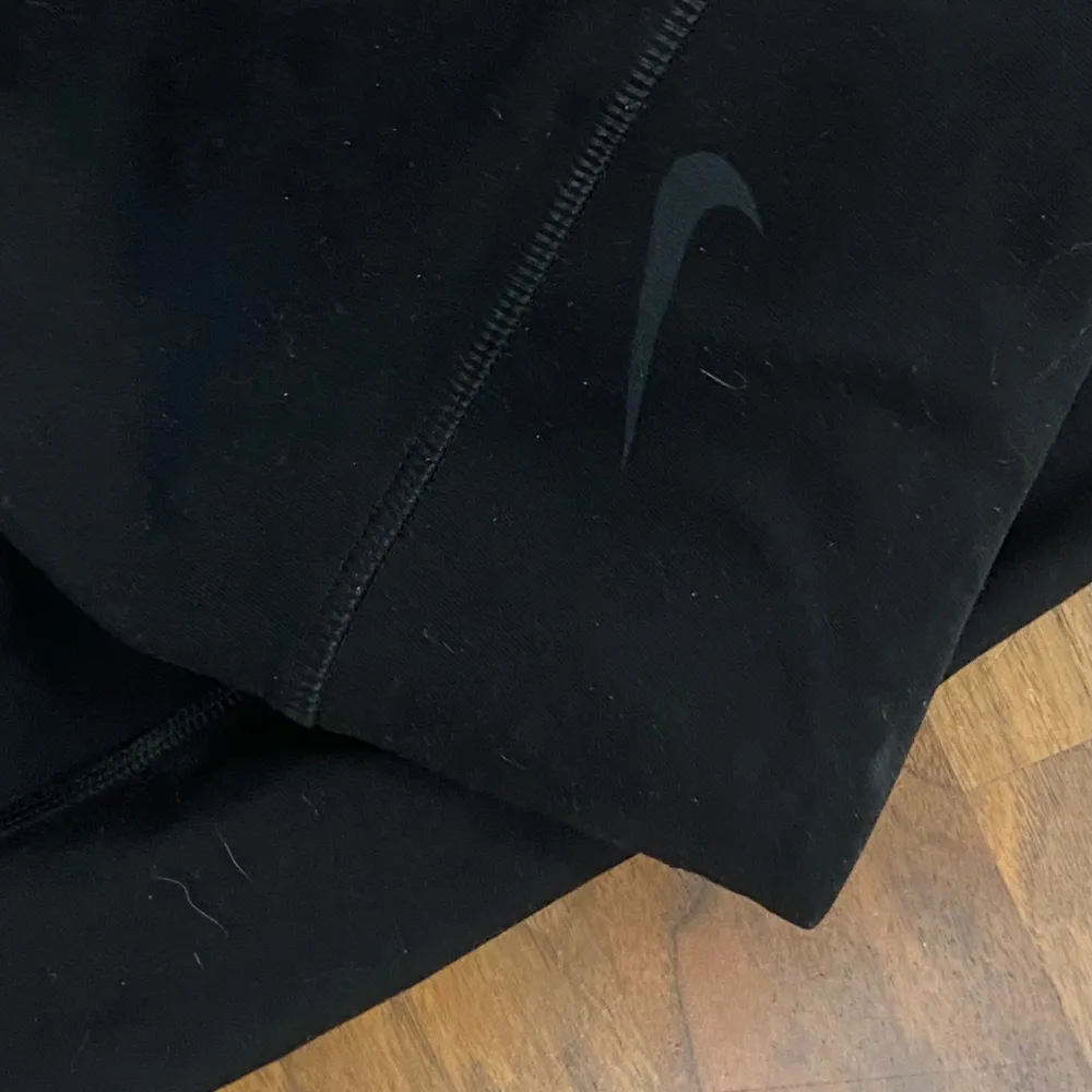 Säljer ett par svarta träningsleggings från Nike i storlek M. De är tillverkade i ett bekvämt och stretchigt material med Dri-FIT-teknologi som håller dig torr under träningen. Leggingsen har en hög midja och en diskret Nike-logga på sidan. Perfekta för gymmet eller löprundan! Djurhår förekommer. Jeans & Byxor.