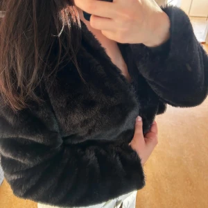 PrettyLittleThing - Cropped Faux Fur Jacket - Säljer en supermjuk och fluffig svart pälsjacka i croppad modell. Perfekt för att hålla sig varm och snygg under kyliga kvällar. Jackan har långa ärmar och en stilren design som passar både till vardags och fest. Ett måste i garderoben för den som älskar att sticka ut! Jackan är helt oanvänd, i nyskick. 