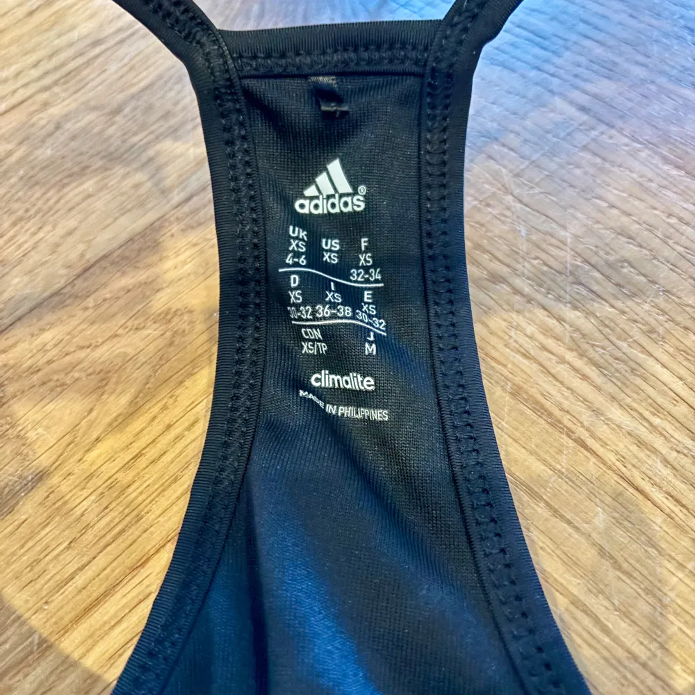 Säljer en svart linnetopp från Adidas i storlek XS. Nästan helny! Snygg med smala axelband. Passar perfekt för gymmet eller löprundan!. Sportswear.