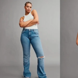 Utställda jeans från Gina Tricot Perfect Jeans - Säljer ett par blå jeans från Perfect Jeans i storlek 32. De är bootcut med en snygg slitning på ena benet. 