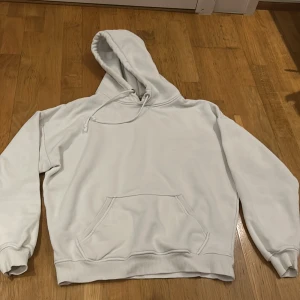 Vit hoodie från BikBok - Säljer en  bekväm vit hoodie från BikBok i storlek S. Perfekt för mysiga dagar eller som ett stilrent basplagg. Den har en klassisk känguruficka och justerbar huva. 