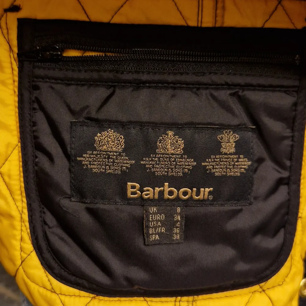 Säljer en snygg svart quiltad väst från Barbour i storlek EUR 34. Västen har gul insida och detaljer som knappar och bälte i midjan. Perfekt för höst och vår, med en stilren look som passar både till vardags och fest.. Jackor.