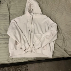 Vit hoodie med dragkedja - Säljer en vit hoodie i mycket bra skick. Den har en dragkedja framtill och en mysig huva. Perfekt för kyliga dagar eller som ett extra lager. Storleken är normal och den passar till det mesta i garderoben. 🧥✨