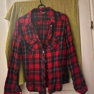 Röd och svart rutig skjorta från Divided - Säljer en snygg röd och svart rutig skjorta från Divided. Skjortan har långa ärmar och knappar framtill. Perfekt för en avslappnad stil eller en cool lager-på-lager look. Passar bra till både jeans och kjol. 🖤