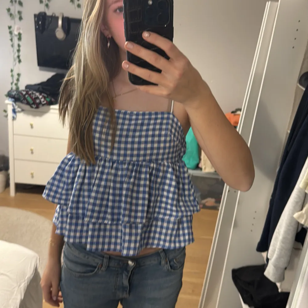 Säljer en superfin blåvit rutig linnetopp med volanger. Perfekt för sommardagar! Toppen har smala axelband och en luftig passform. Passar perfekt till jeans eller shorts för en avslappnad look. 🌞. Yläosat.