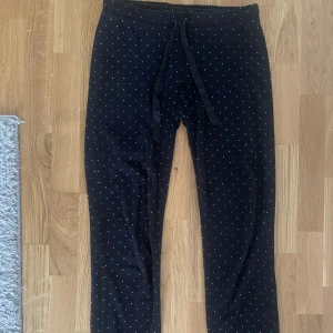 Svarta mjukisbyxor med prickigt mönster🎄❤️ - Säljer ett par svarta mjukisbyxor med små vita prickar. De har en bekväm passform och dragsko i midjan för justerbarhet. Perfekta för en avslappnad dag hemma eller en promenad i parken. Supermysig till jul🎄🎅❤️ passar XS och S