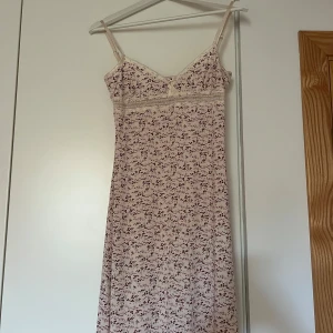 Blommig klänning från Fransa - Söt blommig klänning från Fransa i storlek S. Den har ett ljust blommönster med lila och rosa toner och fina spetsdetaljer vid halsen. 50kr + frakt 