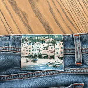 Blå jeans från Jacob Cohen - Payment via paypal/vipps, Säljer ett par snygga blå jeans från Jacob Cohen. De har en klassisk femficksdesign och en cool patch med Portofino-motiv. Jeansen har en normal passform och är perfekta för både vardag och fest. säljs billigt pga skick. har fler bilder