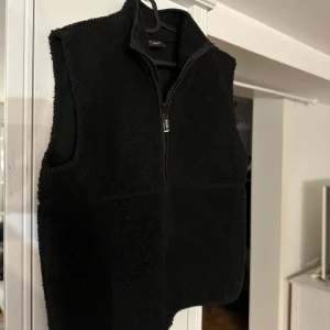 Svart fleeceväst med dragkedja - Säljer en mysig svart Teddy väst perfekt för vinter halvåret! Knappt använd och köpt förra året. 