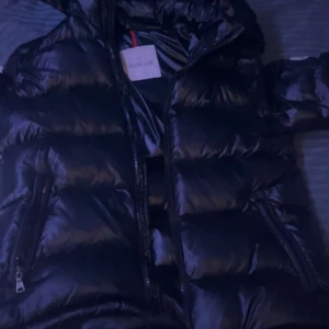 Svart pufferjacka från Moncler - Säljer en snygg svart pufferjacka från Moncler. Den är perfekt för kalla dagar med sitt quiltade mönster och långa ärmar. Jackan har en dragkedja framtill och är i mycket bra skick. Passar perfekt för vintern och hösten!