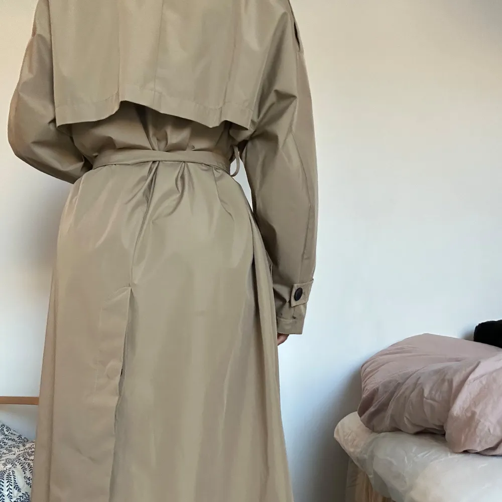 Säljer en klassisk beige trenchcoat i mycket bra skick. Den har ett bälte i midjan och knappar framtill. Perfekt för höst och vår, med långa ärmar och en stilren design. Passar både till vardags och lite finare tillfällen. Passar XS-M.. Jackor.