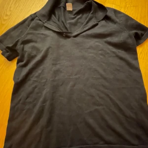 Svart kortärmad tröja från Lindex - Säljer en svart kortärmad tröja från Lindex i storlek 158/164. Tröjan är i bra skick och perfekt för vardagsbruk. Den har en enkel design utan mönster och är tillverkad i ett mjukt material.