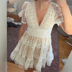 Studentklänning  - Säljer en superfin vit spetsklänning med v-ringning och puffiga kortärmar. Klänningen har ett vackert spetsmönster och en volangdetalj i nederkant. Perfekt för sommarens fester eller midsommarfirande! 💫