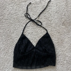Svart glittrig halterneck topp - Snygg svart halterneck topp från Cider med glittriga detaljer. Perfekt för festliga tillfällen! Helt ny med prislapp kvar. 