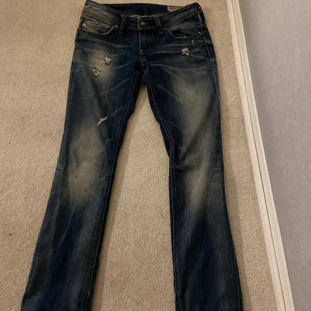 Säljer ett par as snygga Lågmidjade blå jeans från Diesel i modellen Lowky. De har en liten fläck vid knät men annars är dem i bra skick💕Bara att skriva om ni har några frågor🤩. Jeans & Byxor.