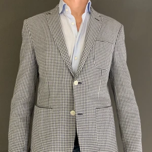 Rutig Sand kavaj i navy och vit - Snygg rutig kavaj i navy och vit med klassisk passform. Perfekt för både formella och semi-formella tillfällen. Kavajen har två knappar framtill och en stilren insida. Passar bra till både jeans och kostymbyxor.
