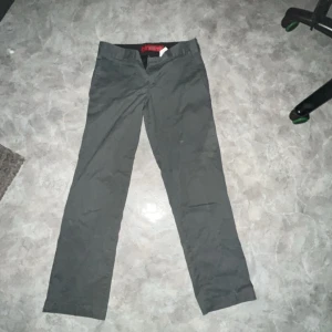 Dickies byxor grå - Säljer ett par grå byxor från Dickies i slim fit. De är perfekta för både vardag och lite mer uppklädda tillfällen. Byxorna har en klassisk design med knapp och dragkedja framtill samt fickor både fram och bak. De är i bra skick och redo för en ny ägare!