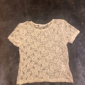 Vit spetsblus från Grunt - Säljer en superfin vit spetsblus från Grunt. Perfekt för sommardagar eller festliga tillfällen. Blusen har korta ärmar och ett vackert spetsmönster.  Söt spelstopp från Grunt som är jätte fin att ha under en kortare t shirt, över ett linne eller under en kofta. Säljer för att jag inte använder den. Det står M på lappen men den är faktist ganska liten så jag skulle nog säga att storleken är xs-s. använd men bara testad.  Aldri