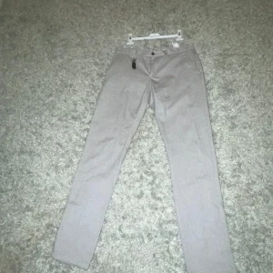 Beige byxor från Zara Man - Säljer ett par stilrena beige byxor från Zara Man i storlek 40. De har en klassisk design med knappar och dragkedja framtill. Perfekta för både vardag och festliga tillfällen. Passar bra till höst och vår.