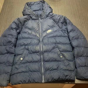 Nike tjock vinterjacka 100% polyester  - Använd Nike vinterjacka! Jackan är i bra skick med små blekningar! Storlek M i barn vilket är 137-147 men passar även till lite större barn. Hör av dig vid funderingar! Köparen står för frakten! 100% polyester