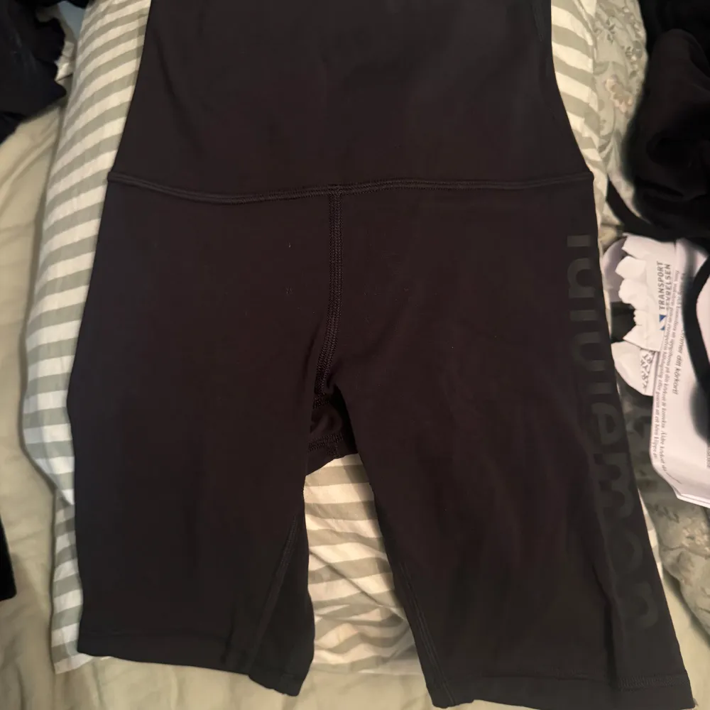 Säljer ett par svarta cykelshorts från Lululemon i mycket bra skick. De är perfekta för träning och har en hög midja för extra komfort. Materialet är stretchigt och andas bra, vilket gör dem idealiska för intensiva pass. Lululemon-loggan syns diskret på benet. Passar perfekt för sommarens alla träningspass! Storlek s. Shorts.