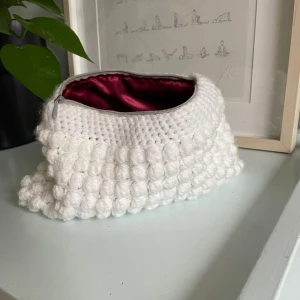 Virkad necessär  - Superfin virkad necessär med bubblig textur. Perfekt julklapp till mamma, kompis, syskon, passar till alla! Insidan är klädd i ett lyxigt rött satinmaterial och den stängs med en dragkedja. Perfekt för att förvara smink eller andra småsaker. Passar perfekt som en söt accessoar i väskan eller på resan! Egen gjord🧶