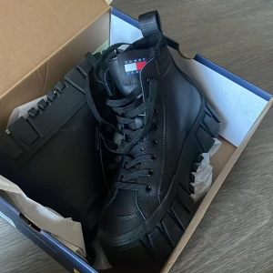 Svarta sneakers från Tommy Jeans - Säljer ett par svarta sneakers från Tommy Jeans i nytt skick. Skorna har en robust sula och snörning framtill. Perfekta för höst och vår med sin stilrena design och bekväma passform. HELT NYA köpta för 1599kr säljer för 900