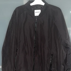 Svart bomberjacka från Bershka - Säljer en stilren svart bomberjacka från Bershka. Jackan har en dragkedja framtill och är i ett lätt och bekvämt material, perfekt för vår och höst. Den har en klassisk bomberstil med ribbade muddar vid ärmslut och krage. Passar både till vardags och fest!