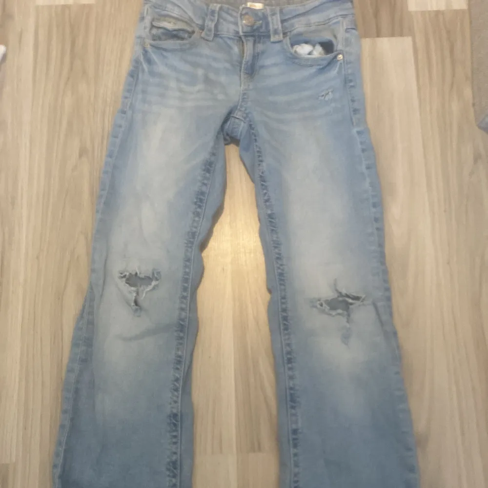 Säljer ett par ljus blåa jeans från Gina Tricot i storlek 152. De har en cool slitning på knäna och en klassisk femficksdesign. Perfekta för en avslappnad stil! 🕶️!!PRIS KAN DISKUTERAS !!. Jeans & Byxor.