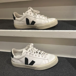 Vita sneakers från Veja - Säljer ett par  vita sneakers från Veja i rätt bra skick. De har en klassisk design med svarta detaljer och snörning. Sulan är i gott skick med lite slitage och även lite skrynkliga på skon men annars är de både snygga och bekväma! ( pris gör att diskutera)