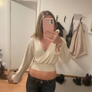 Vit omlottopp - Säljer en superfin vit omlottopp med långa ärmar. Den är croppad och har en snygg v-ringning som passar perfekt till både vardag och fest. Materialet känns mjukt och skönt mot huden. Perfekt för vår och sommar! Säljer då den inte längre kommer till användning. Pris kan diskuteras🩷