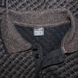 Brun tröja från Monte Carlo - Säljer en brun tröja från Monte Carlo med ett unikt texturerat mönster. Tröjan har långa ärmar och en klassisk krage med knappar. Perfekt för höst och vinter, den är både stilren och bekväm. Passar bra till både vardag och lite finare tillfällen.